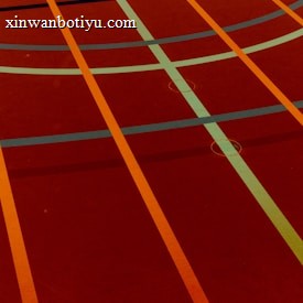 A sports court with intersecting lines in orange and blue, creating geometric patterns on a reddish-brown surface.